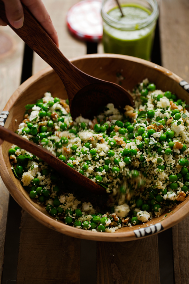 hands tossing couscous salad with peas