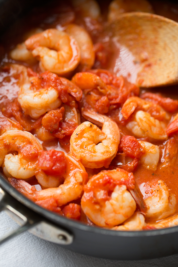 spicy shrimp and tomato mixture in saute pan with wooden spoon