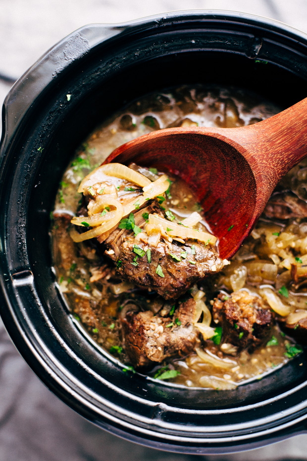 wooden ladle lifting onion pot roast from slow cooker