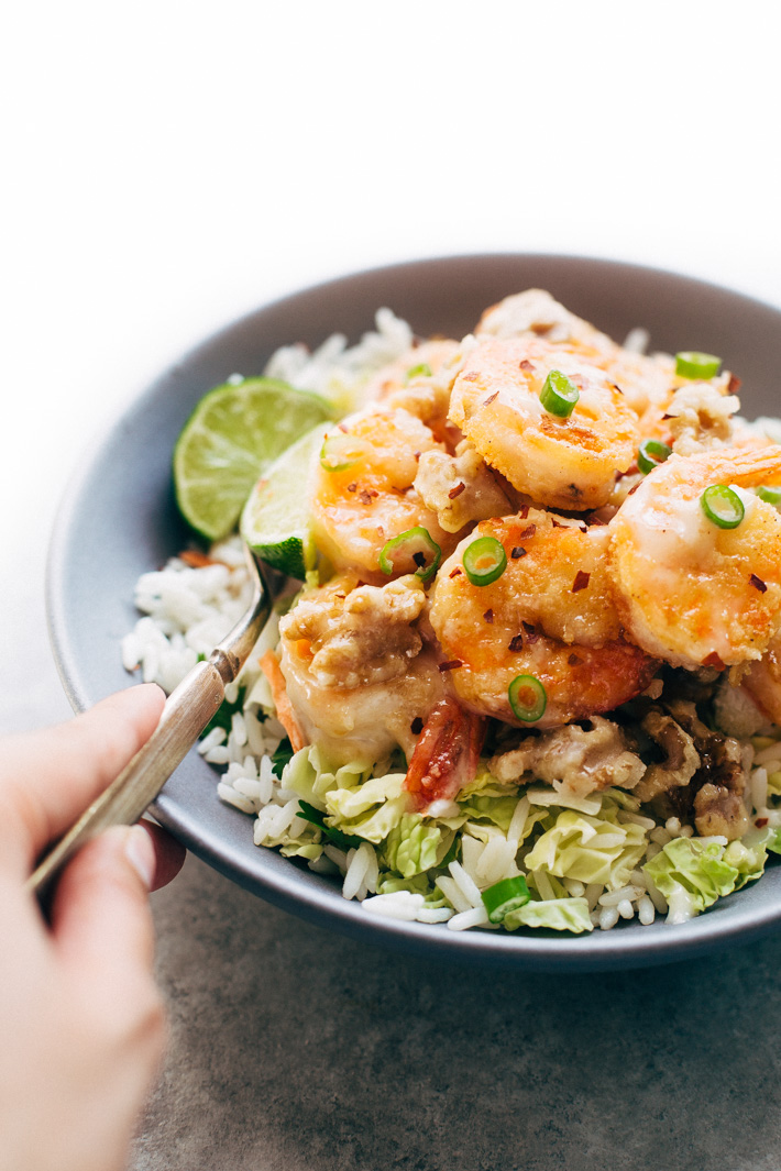 Lighter Honey Walnut Shrimp - A lighter take on the takeout classic! We're pan frying the shrimp in just a hint of oil, tossing it together with candied walnuts and a creamy sauce then serving it over a big mound of greens and rice! #honeywalnutshrimp #takeoutfakeout #walnutshrimp #shrimp | Littlespicejar.com