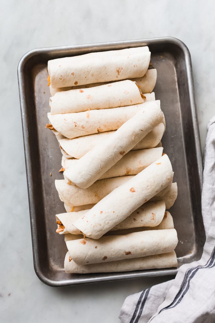 Easy Cheesy Chipotle Chicken Taquitos - Learn how to make flautas or taquitos at home! This recipe can easily be made with rotisserie chicken if you'd like to get this on the table super fast! #flautas #taquitos #superbowl #superbowlfood #appetizers #chickenflautas #chickentaquitos #cincodemayo | Littlespicejar.com