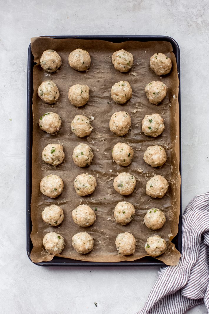 uncooked chicken meatballs on a baking sheet