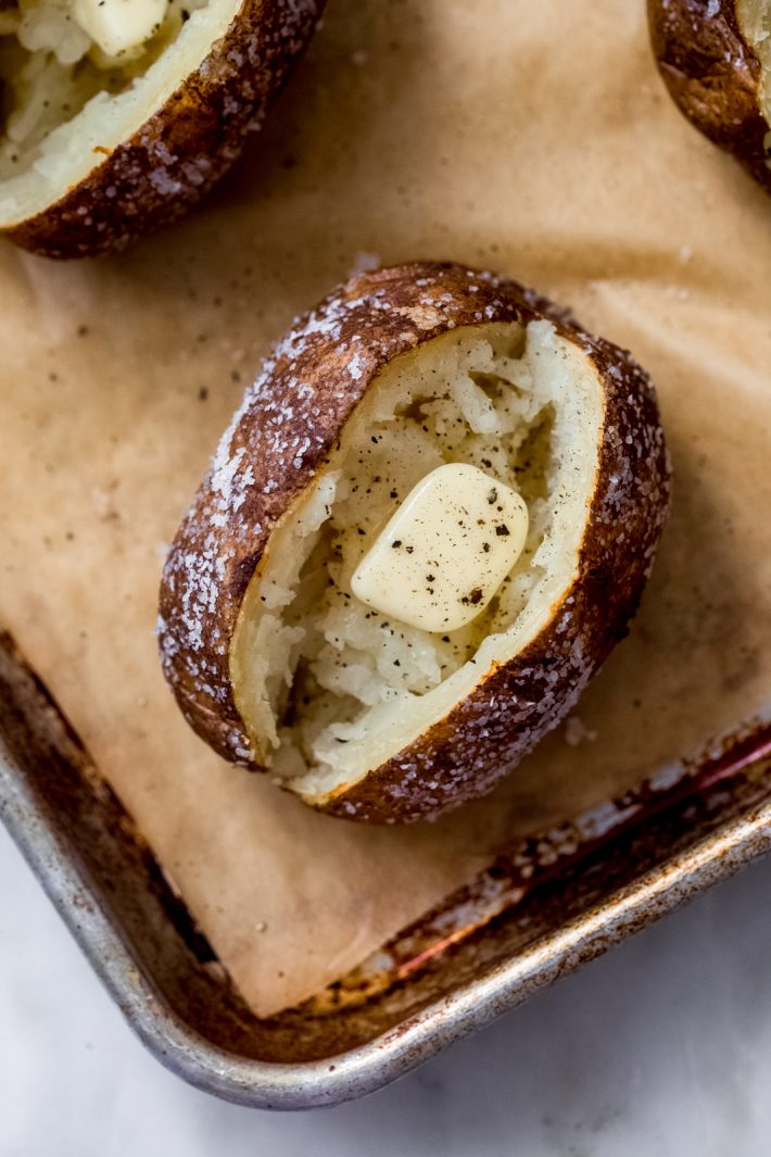 fluffed baked potato with melting butter and pepper