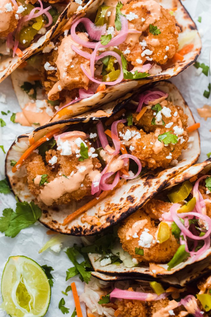 Baja Shrimp tacos topped with pickled onions, cilantro, queso fresco on white parchment