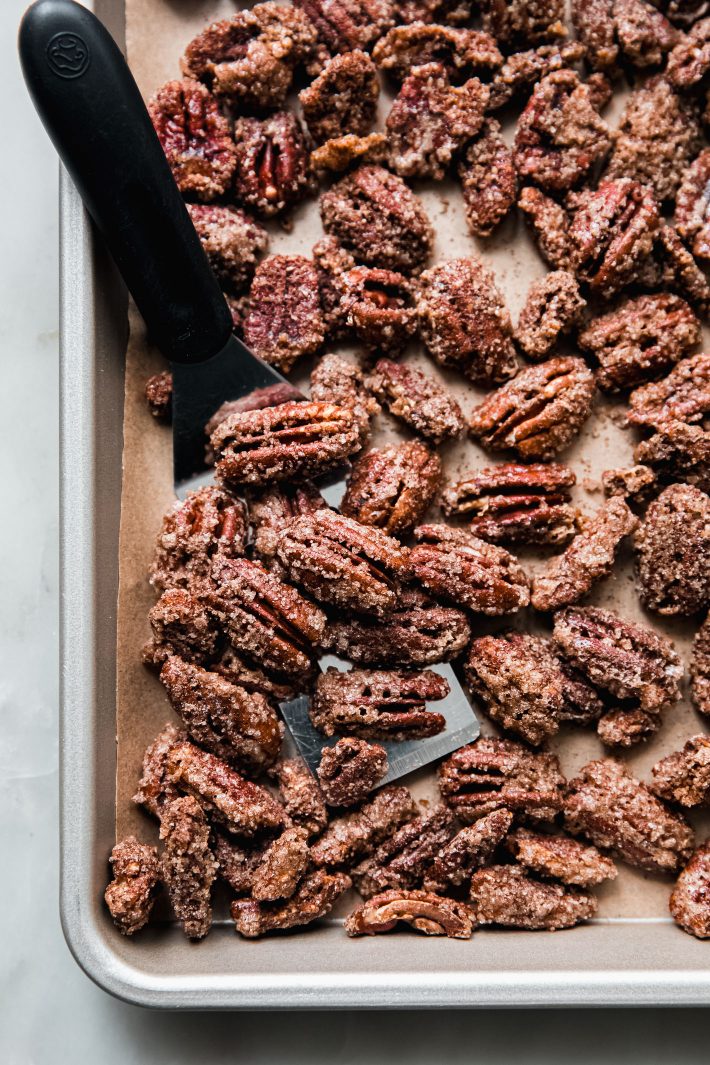 candied pecans on baking sheet with spatula