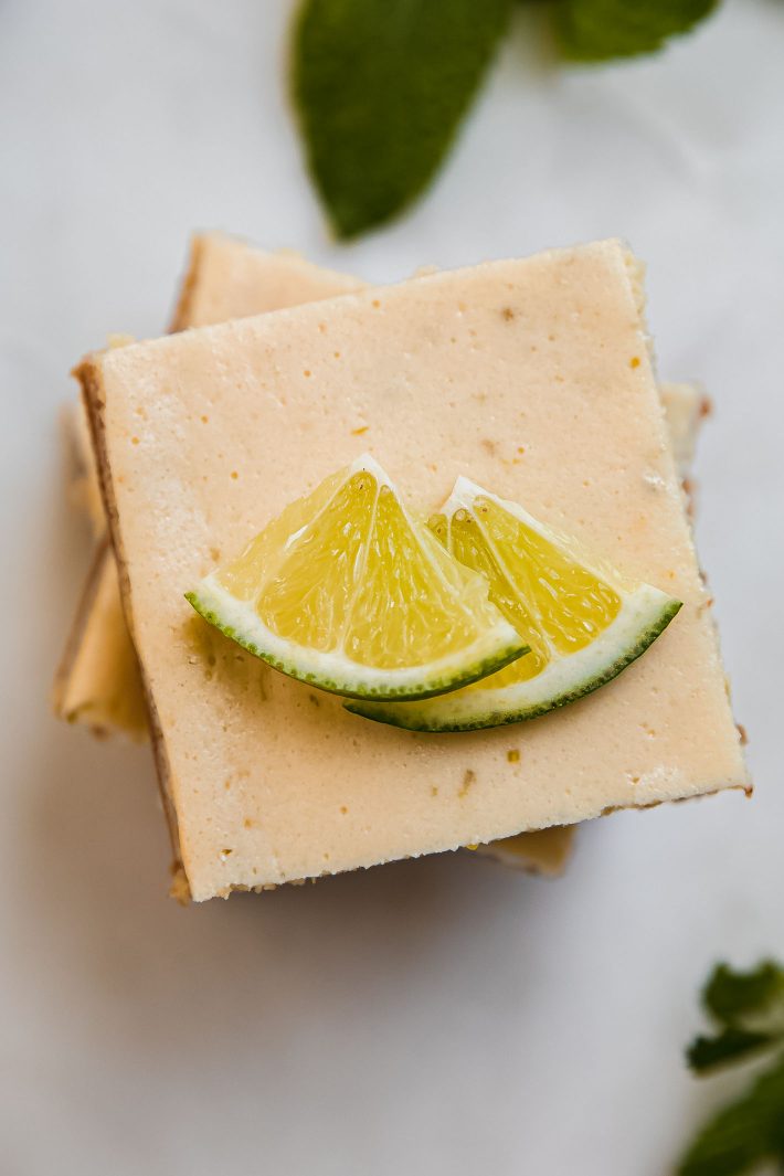 stacked key lime pie bars on marble with lime slices