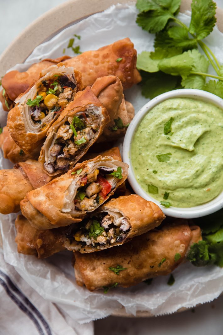 cut up southwestern egg rolls on plate with avocado sauce