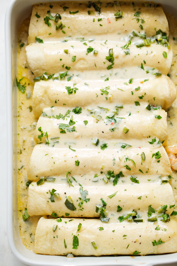 Shrimp Enchiladas with Creamy Poblano Sauce - Simple and delicious shrimp enchiladas stuffed with fresh baby spinach and matchstick carrots. Then drizzle with the creamiest cheese and poblano sauce! #shrimpenchiladas #enchiladas #seafoodenchiladas #mexicanfood | Littlespicejar.com @Littlespicejar