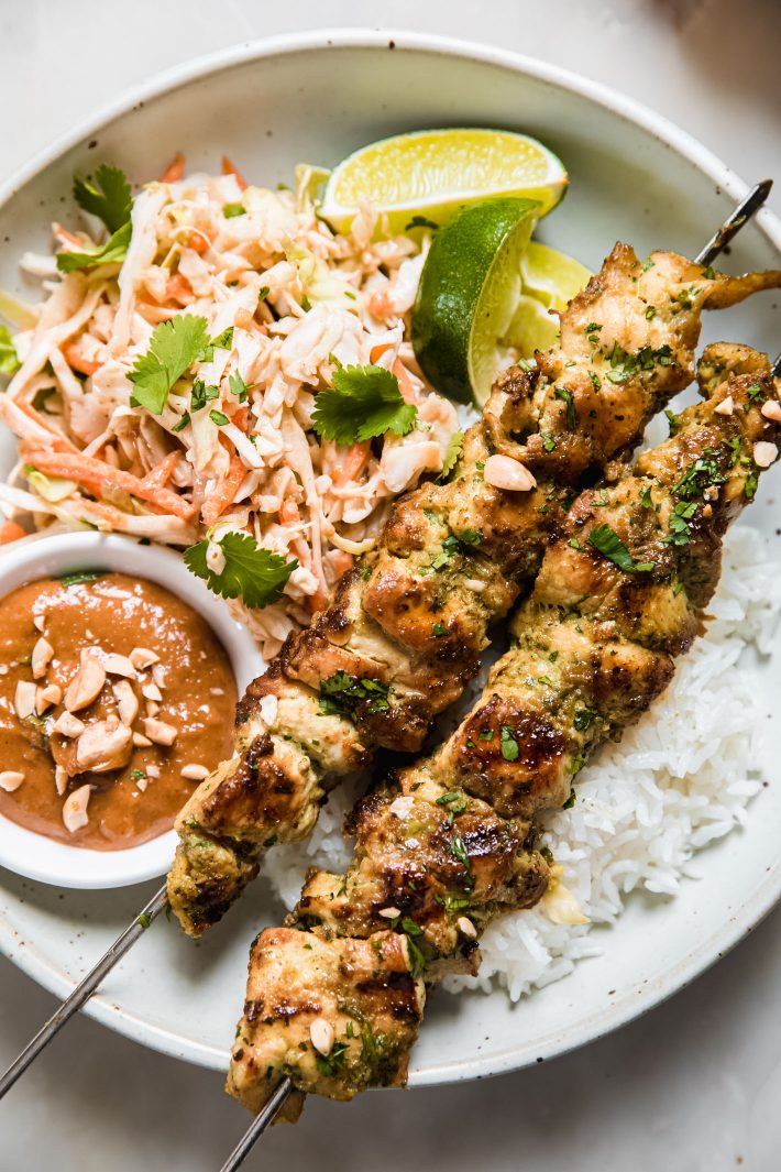 chicken satay on plate over coconut rice with peanut sauce