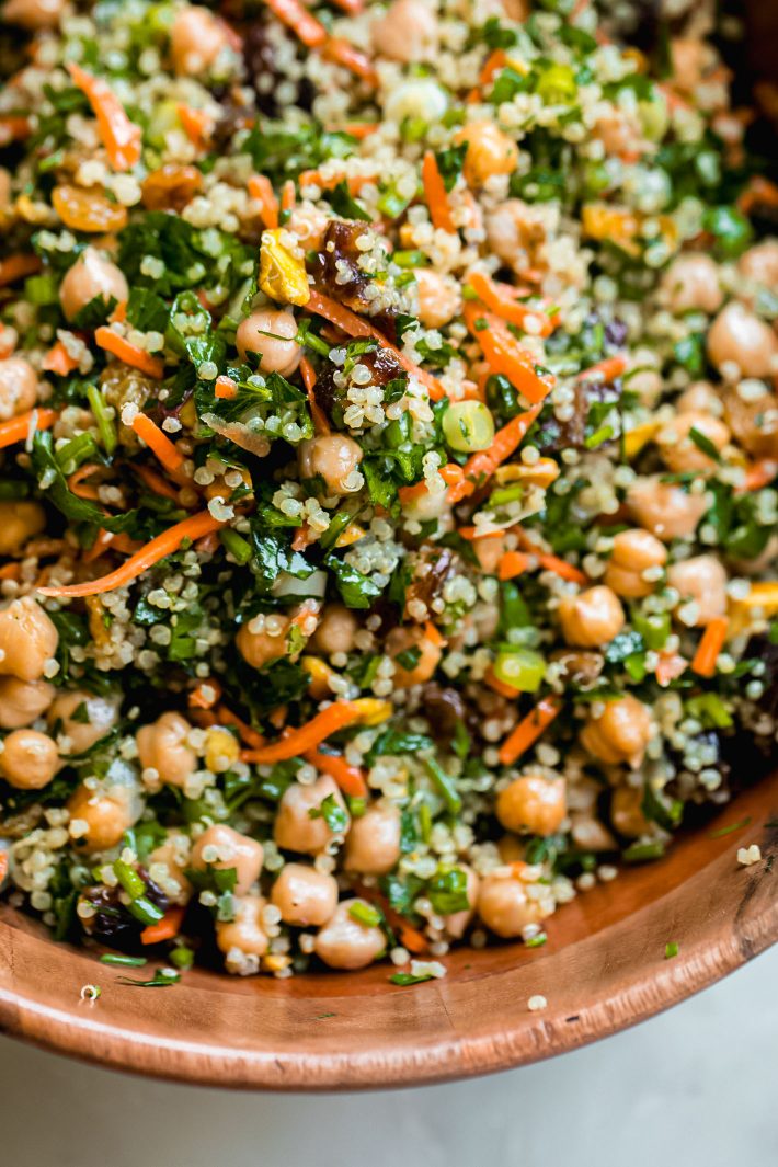 dates, parsley, scallions, carrots, and chickpeas tossed with quinoa in wooden bowl