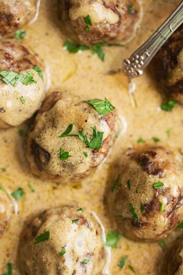 close up of browned meatballs drizzled in Swedish brown cream sauce and sprinkled with parsley