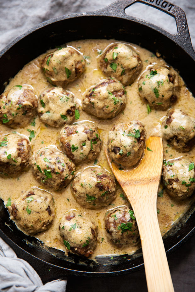 cast iron skillet with Swedish meatballs covered in brown cream sauce