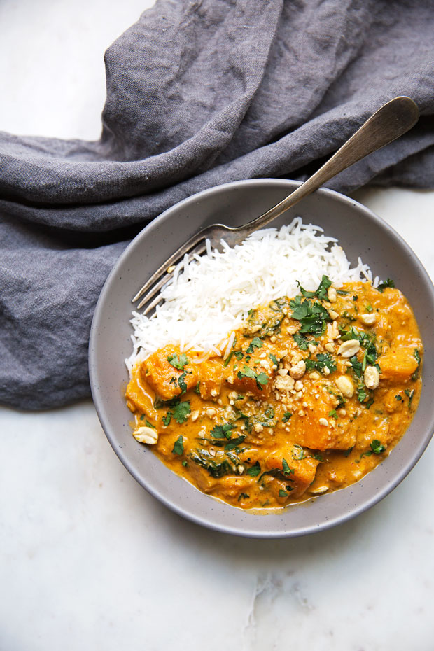 vegetarian red curry in bowl with fork and fluffy basmati rice on white marble
