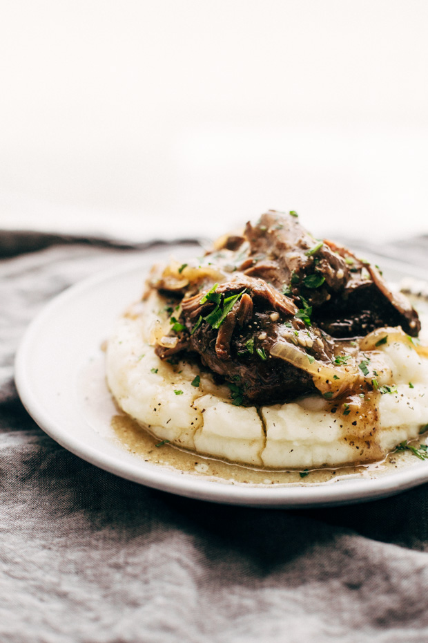 plate with mashed potatoes topped with pot roast and caramelized onions