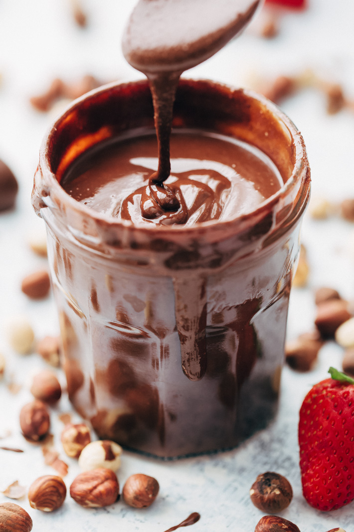 drizzling homemade Nutella from a spoon into glass jar