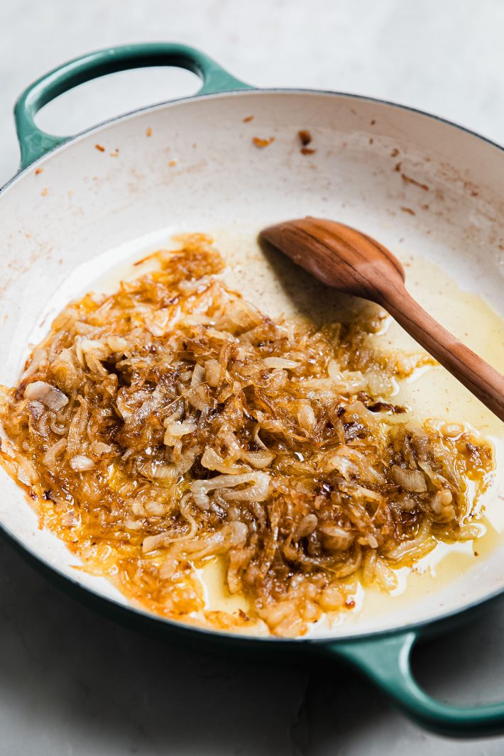 caramelized onions in dutch oven with wooden spoon
