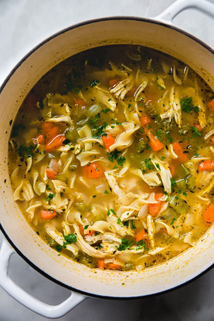 dutch oven filled with chicken soup topped with parsley