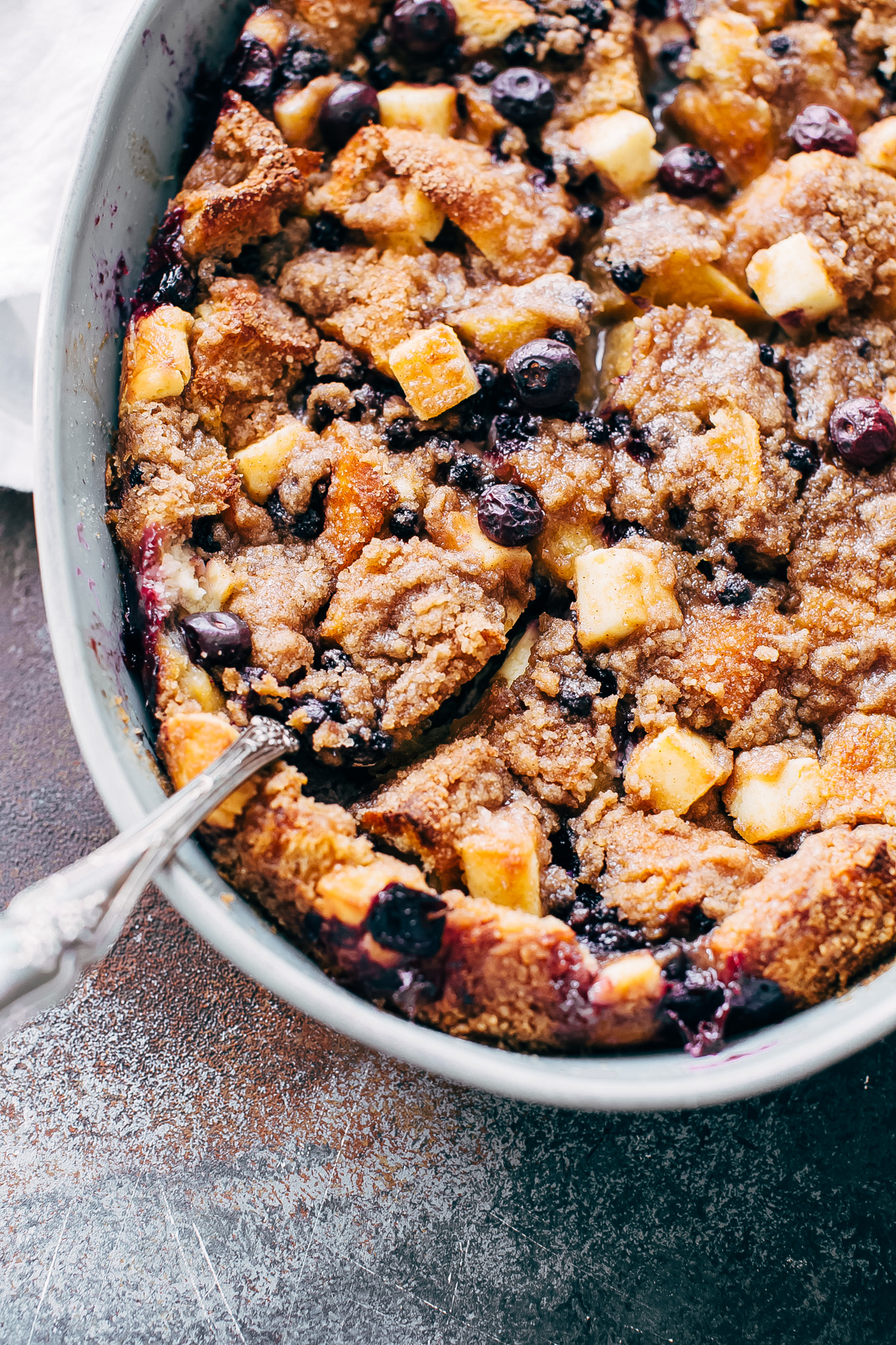 close up of cheesecake French toast casserole with blueberries being scooped with spoon