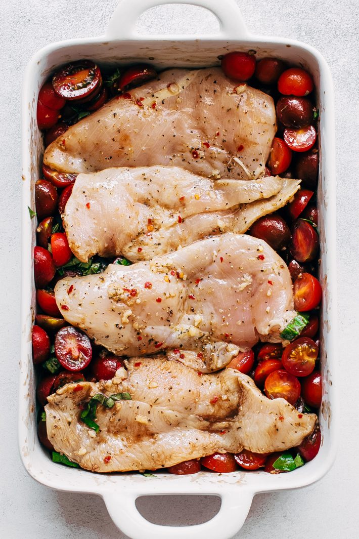 raw chicken placed on top of balsamic tomatoes