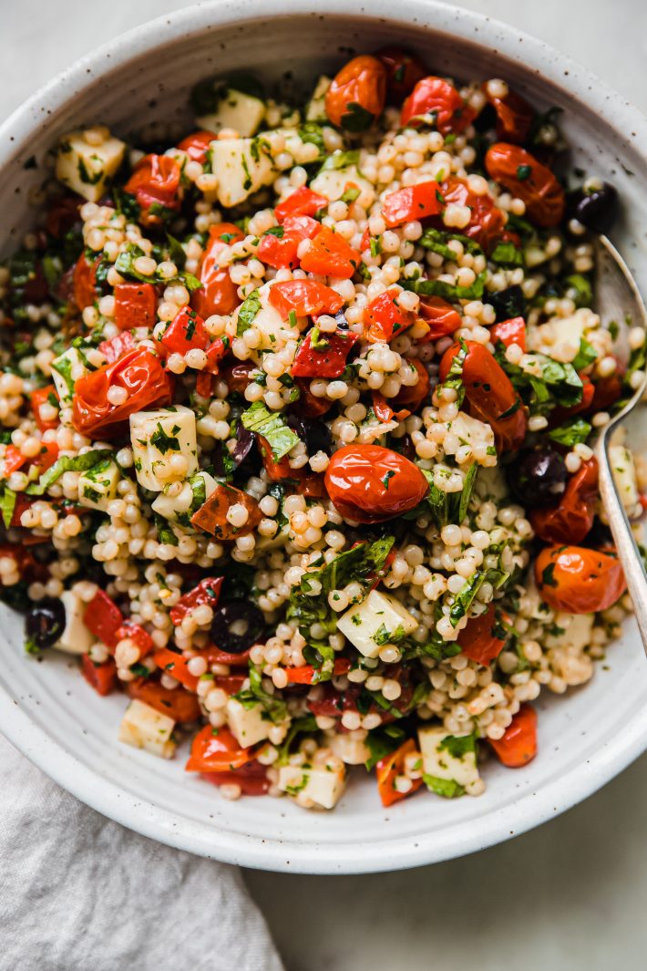Italian couscous salad in a bowl with spoon