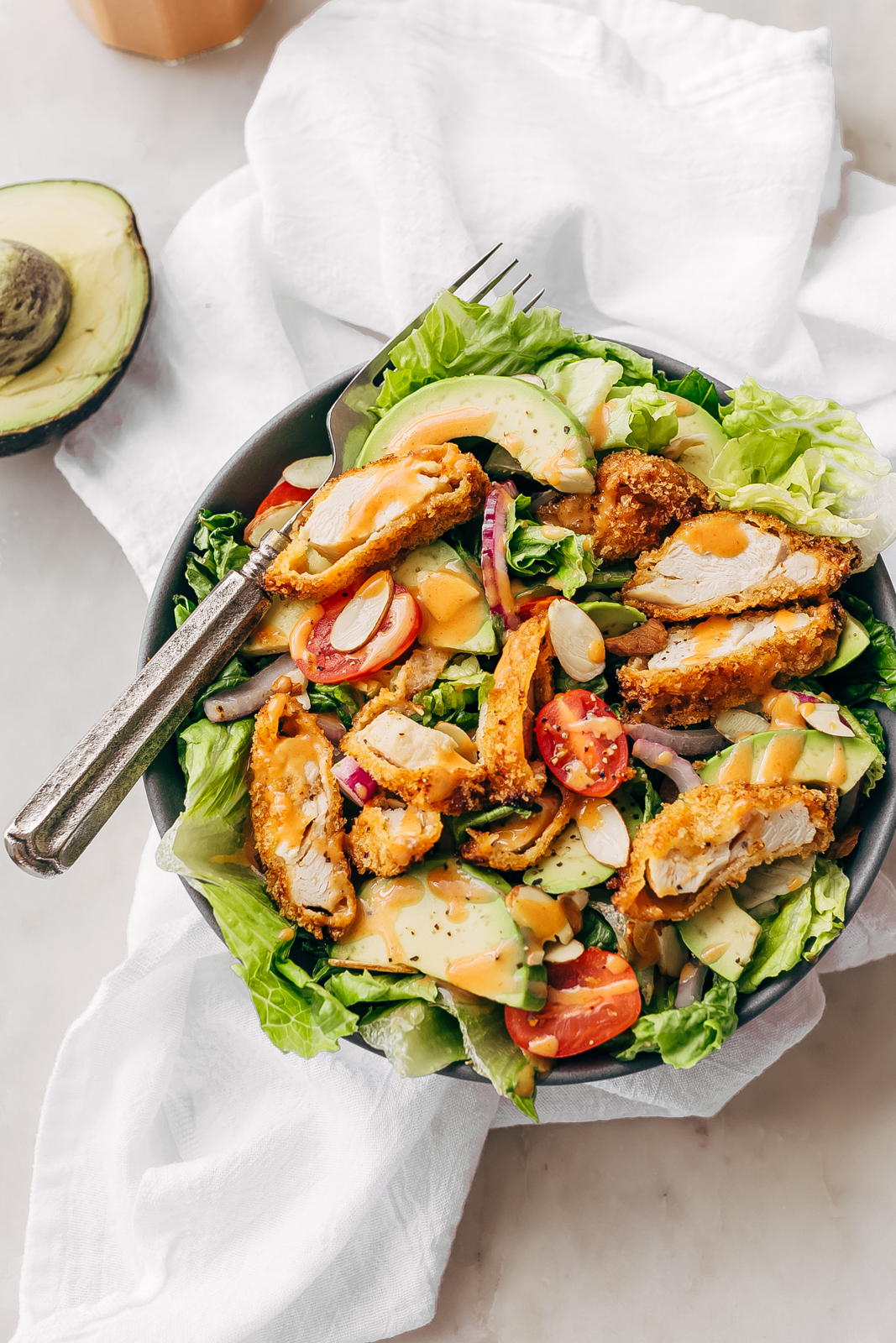 crispy chicken salad with honey sriracha dressing in bowl on white surface