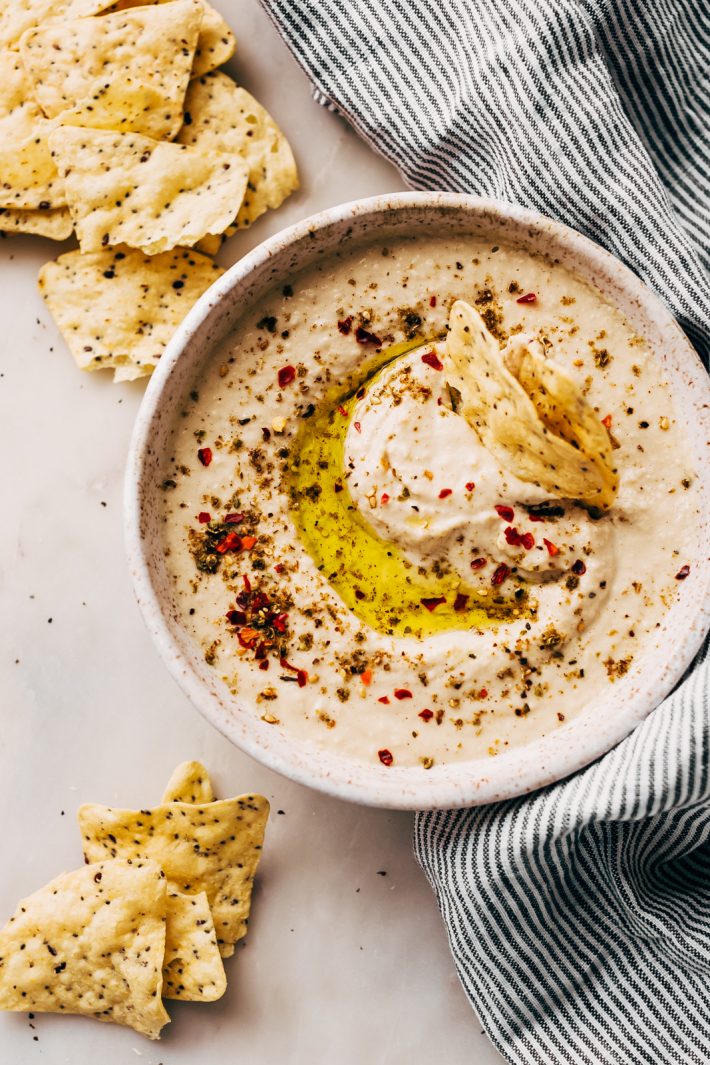 creamy hummus in speckled bowl topped with zaatar on top