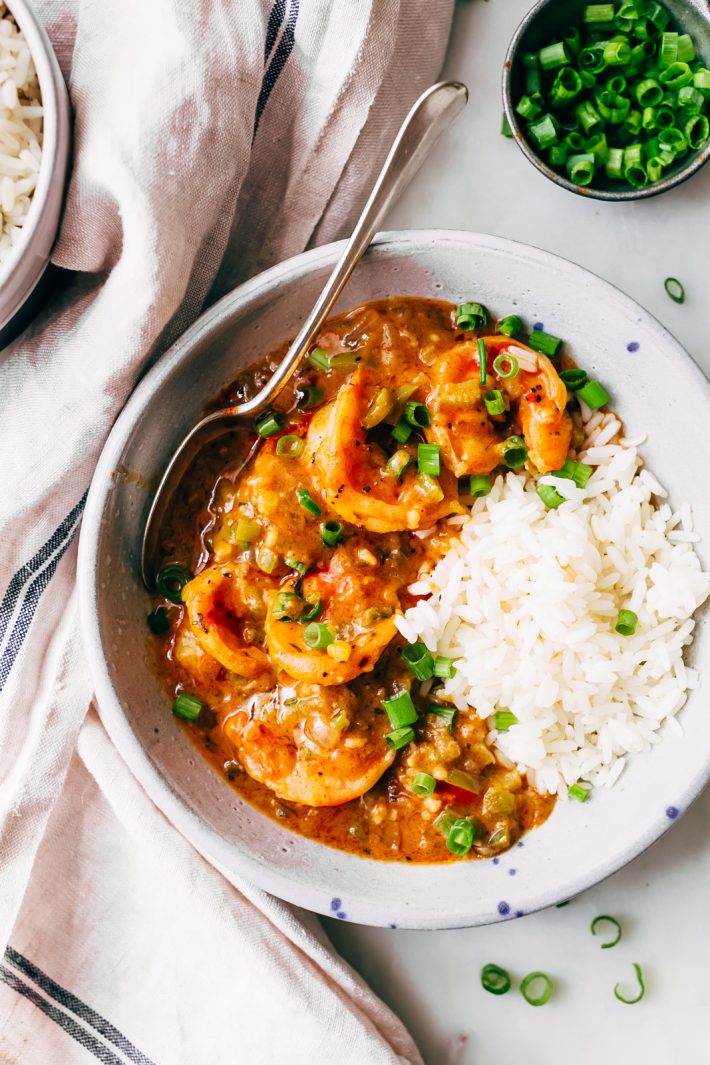 bowl of prepared shrimp étouffée in speckled bowl with rice topped with chopped scallions
