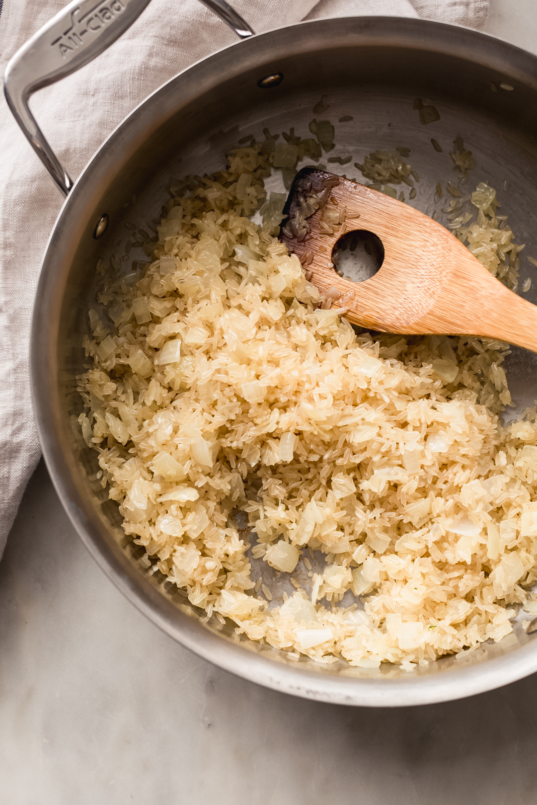 sautéed onions and rice with wooden spoon in pan