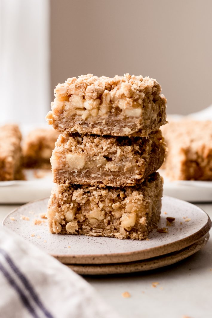 stack of three apple crumble bars on a stack of speckled plates
