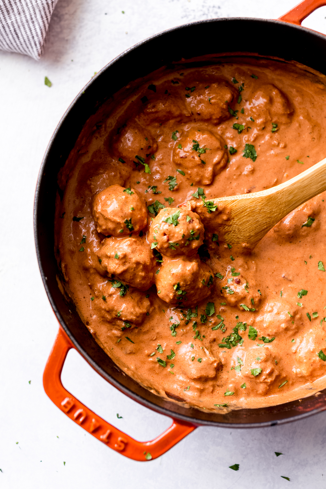 cast iron pot with wooden spoon and chicken meatballs in chipotle butter chicken sauce