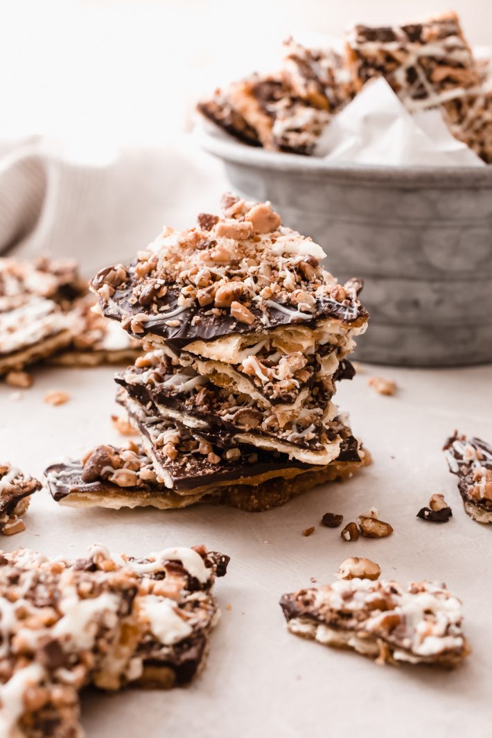 chocolate saltine toffee bark broken and made into a stack on grey surface 