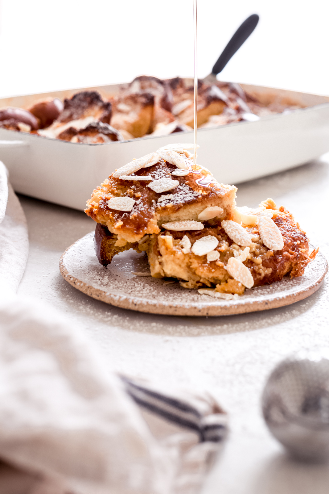 plate holding French toast casserole with maple syrup drizzling on top