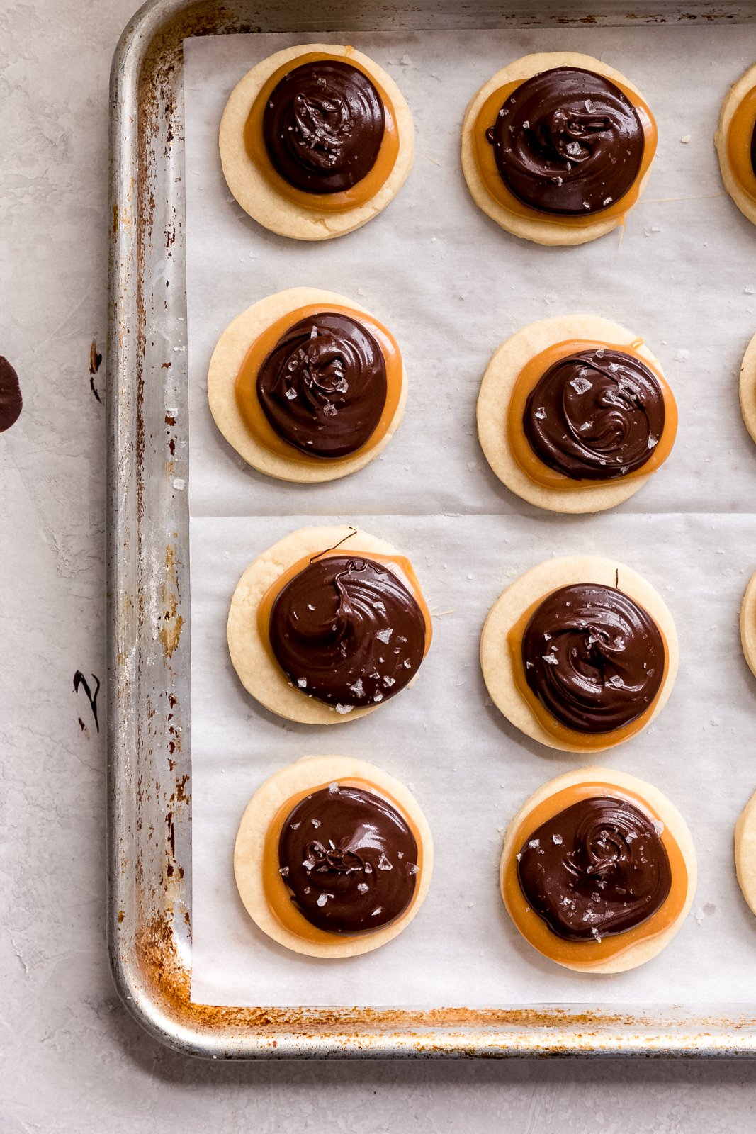 shortbread cookies topped with caramel and chocolate dollops on sheet pan 