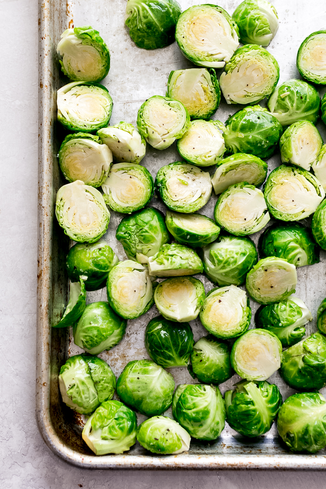 sheet pan with halved sprouts sprinkled with salt and pepper