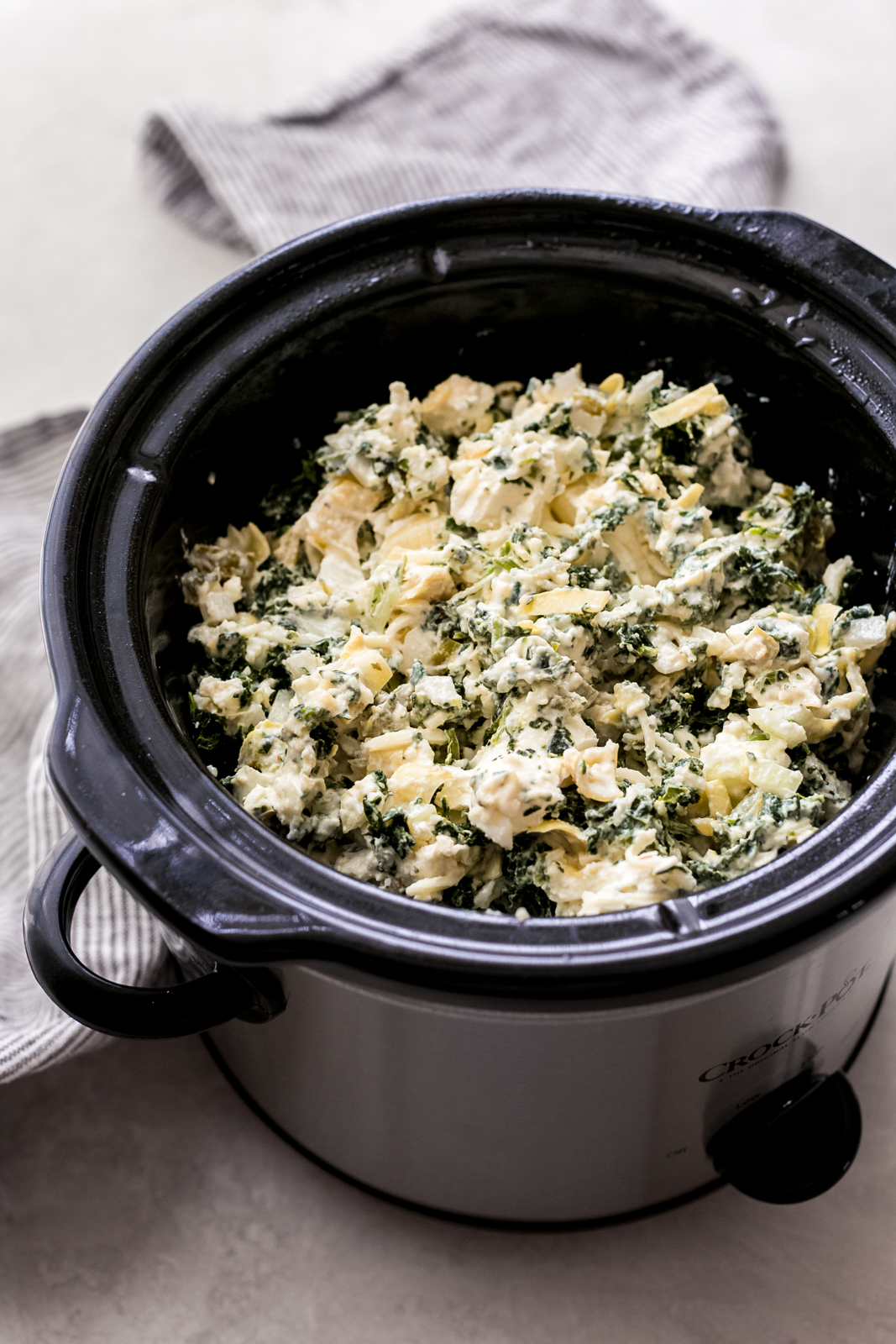 slow cooker loaded with mixed spinach dip ingredients before cooking