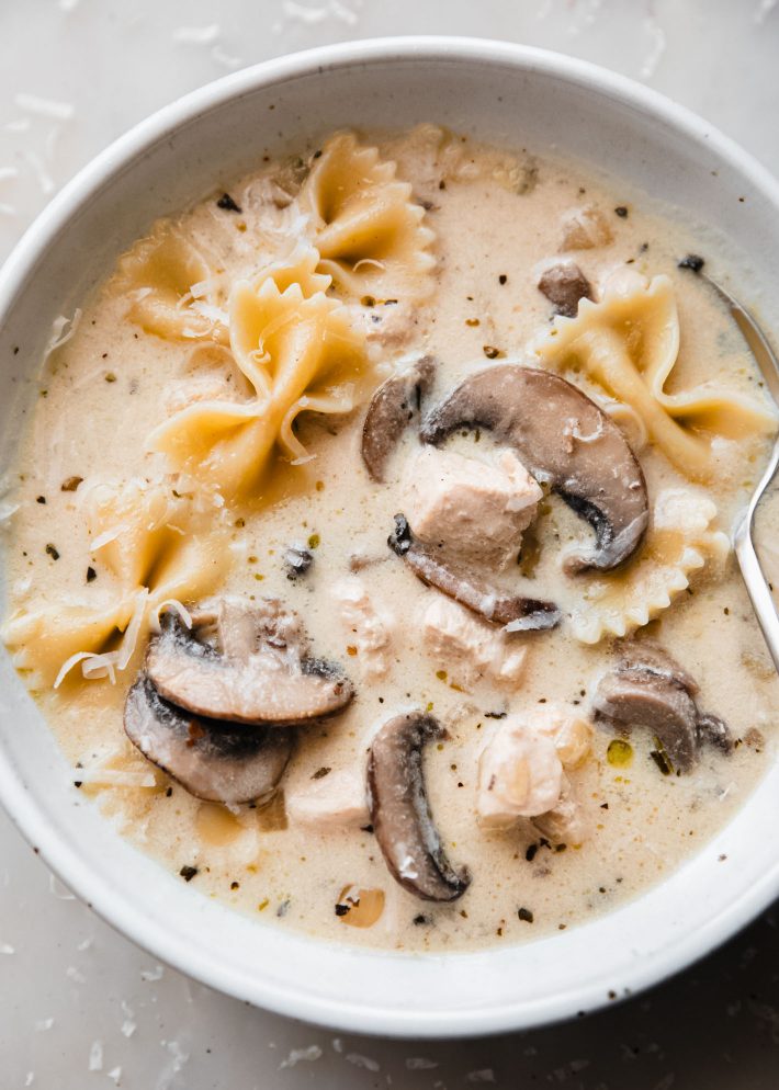 bowl of soup with. mushrooms, bow tie pasta, and parmesan