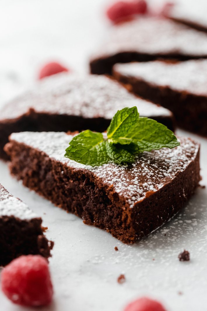 slice of Caprese cake dusted with powdered sugar and topped with mint leaves
