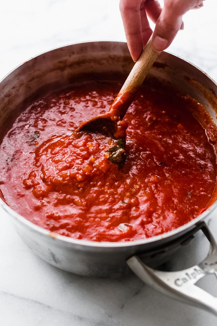 Arrabbiata Sauce in sauce pot being lifted by wooden spoon