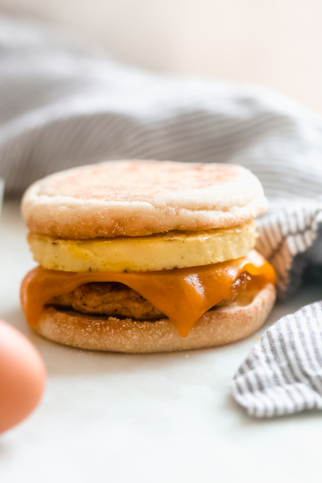 close up of English muffin sandwich with chicken sausage Pattie, melted cheese, and eggs 