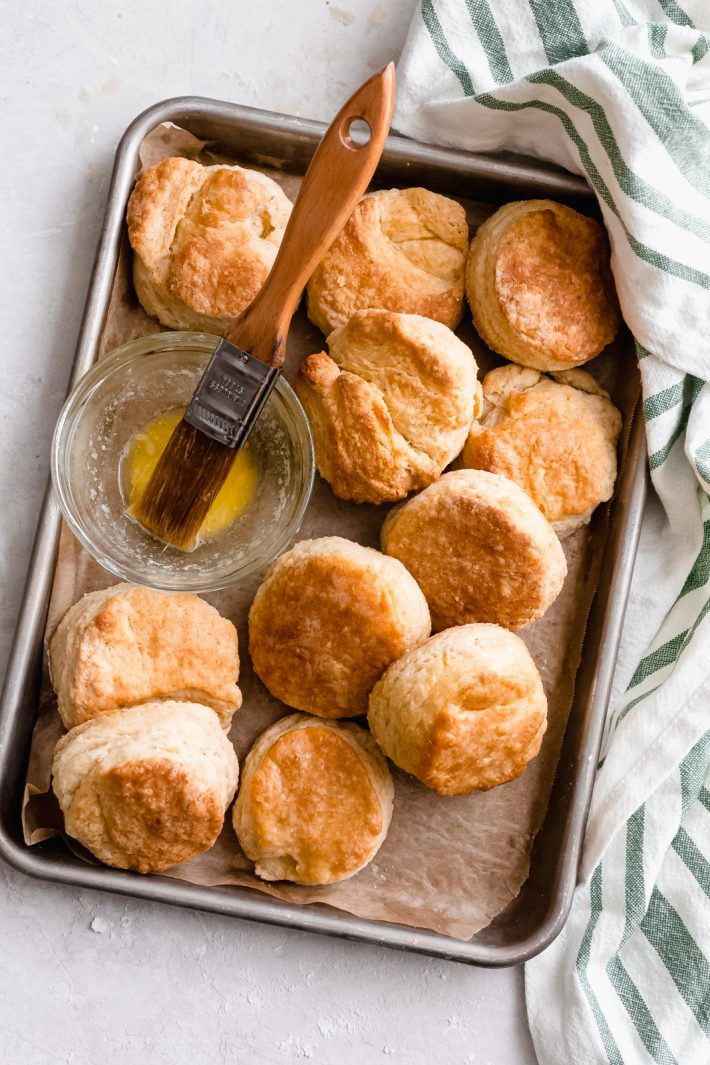 sheet pan with prepared buttermilk biscuits and a bowl of melted butter