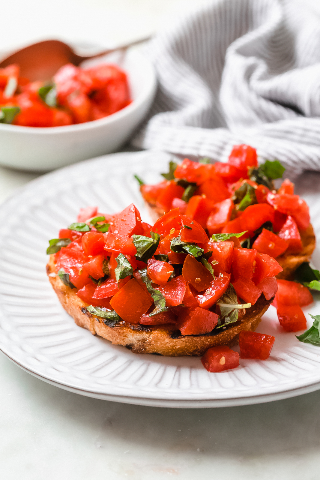 plate with slices of grilled bread topped with tomato bruschetta mixture