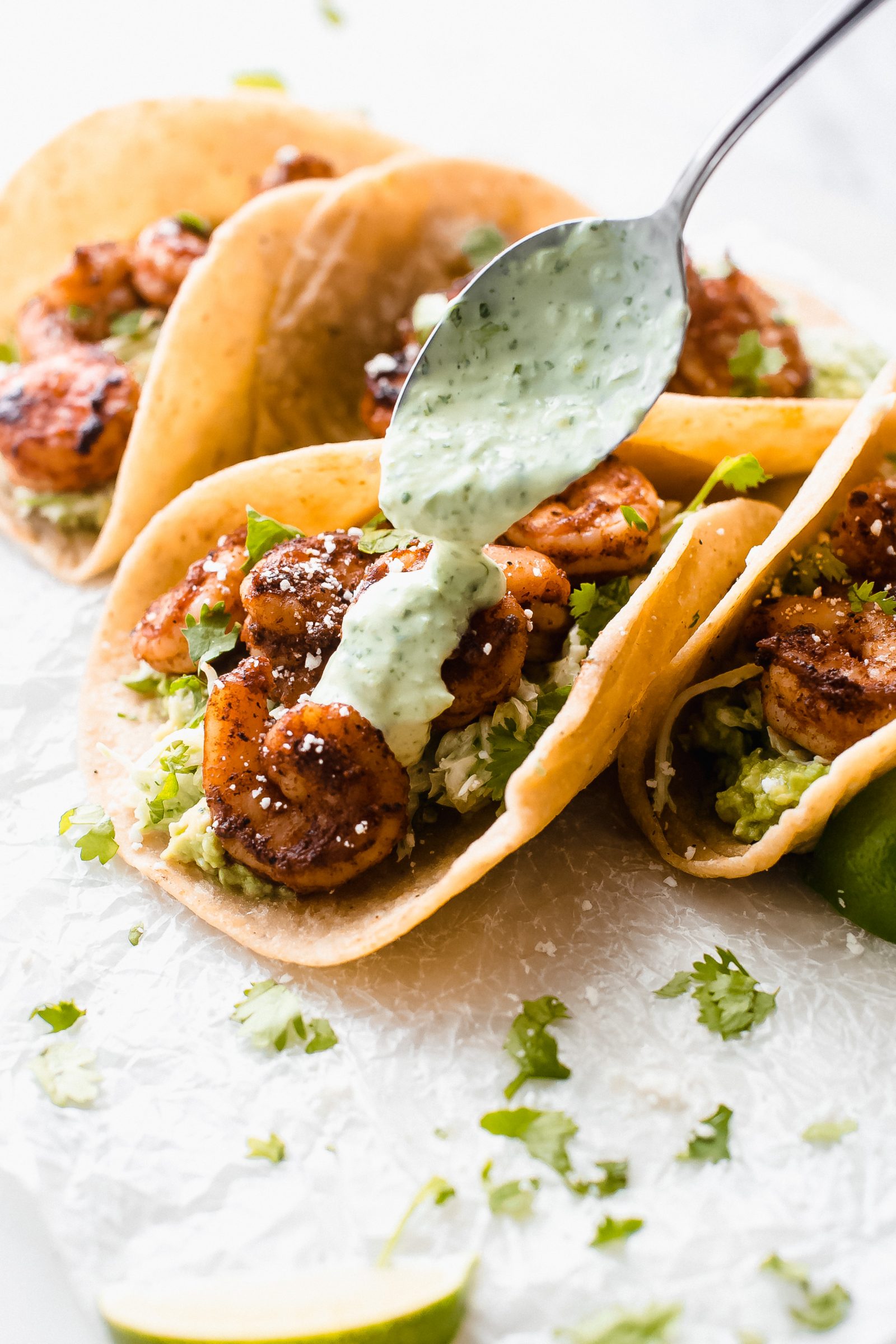 drizzling jalapeno lime crema on blacked shrimp tacos with spoon