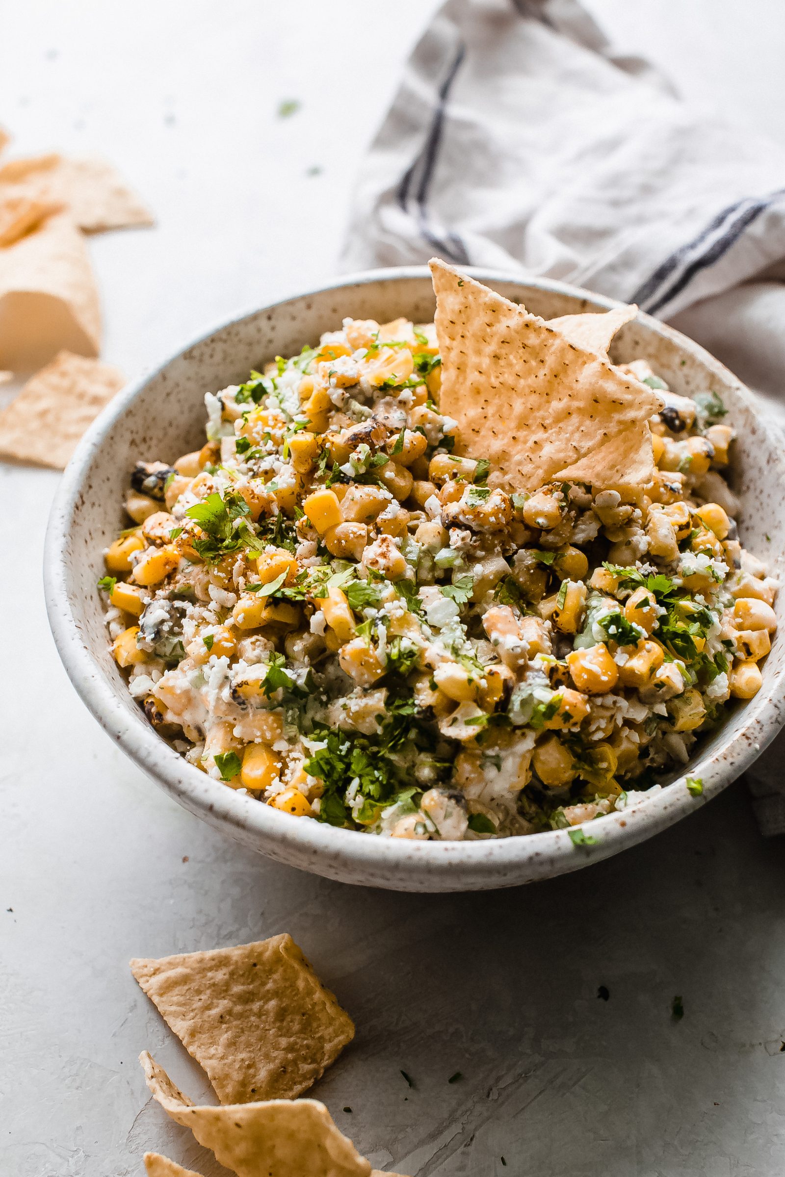 speckled bowl with Mexican corn dip, with tortilla chips standing in bowl