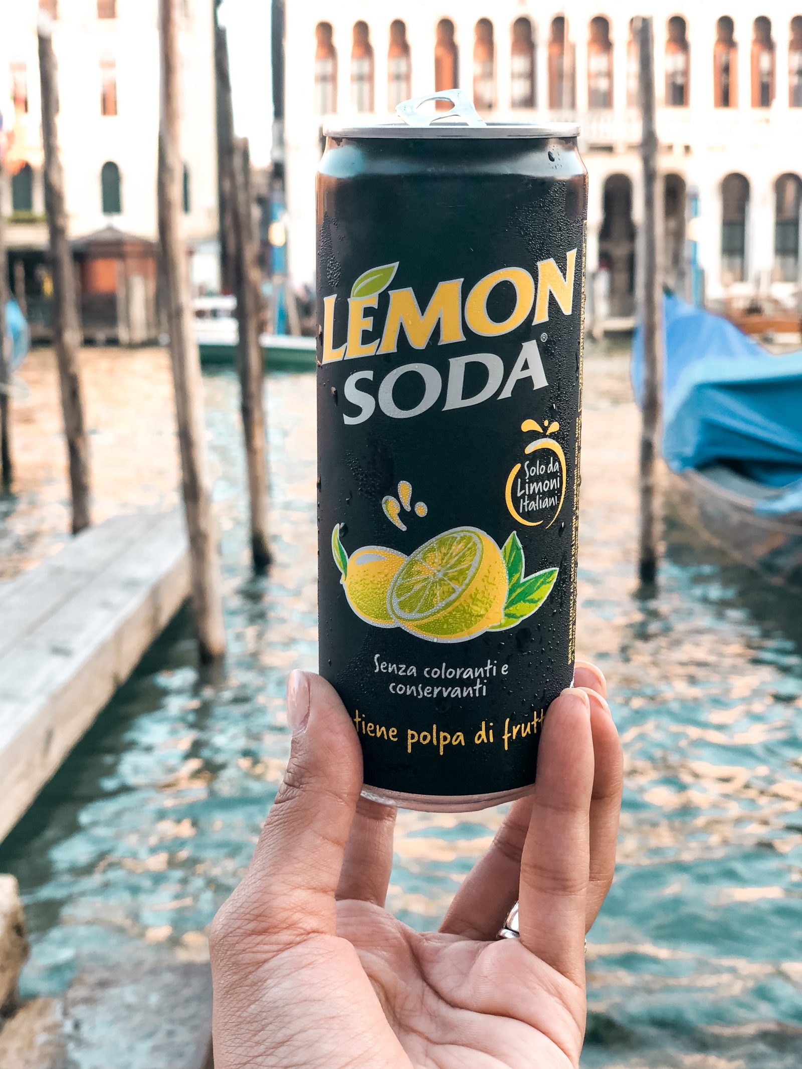 a can of lemon soda with water in the background