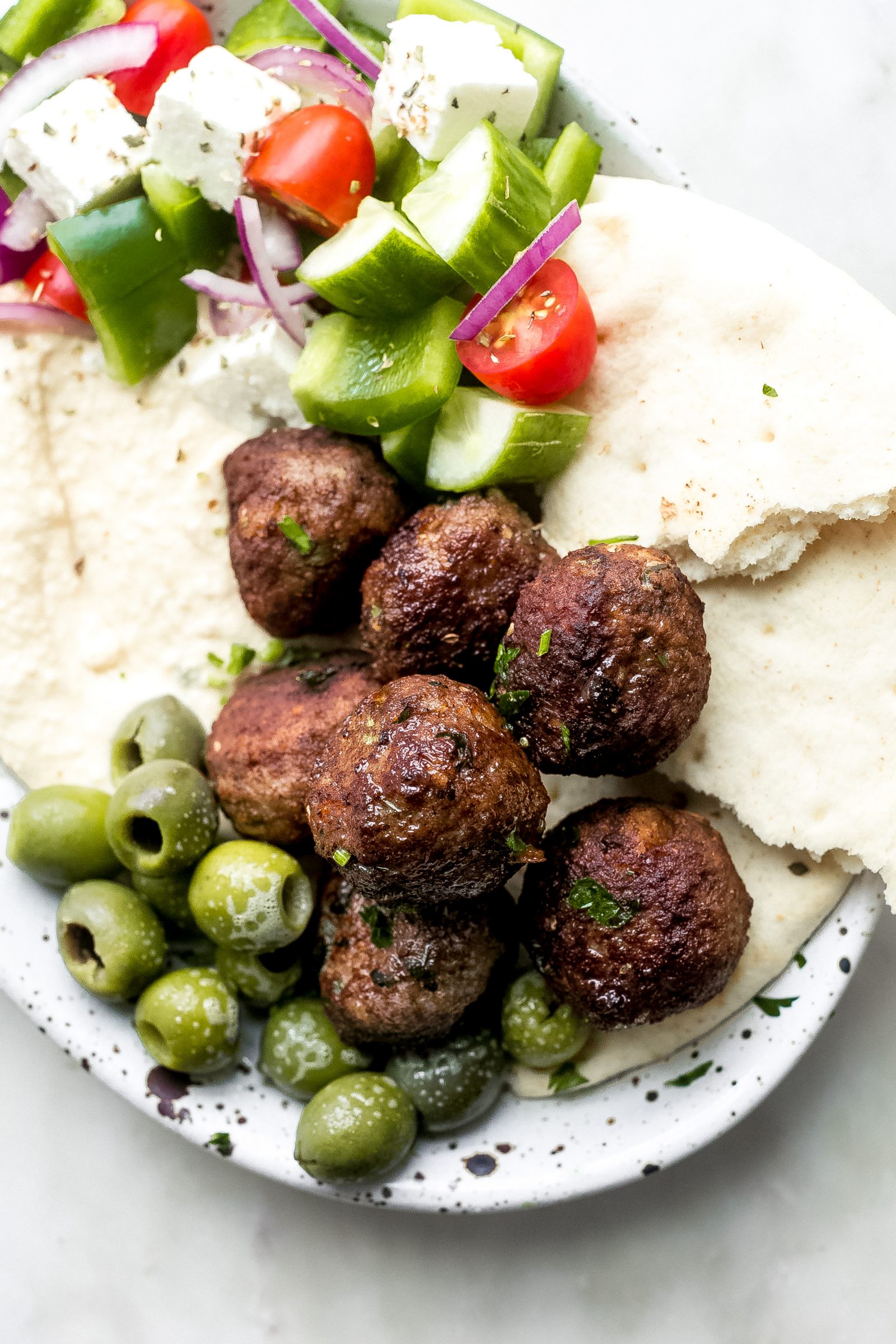 Greek Meatballs on platter with green olives, torn pita bread, Greek Salad, and hummus