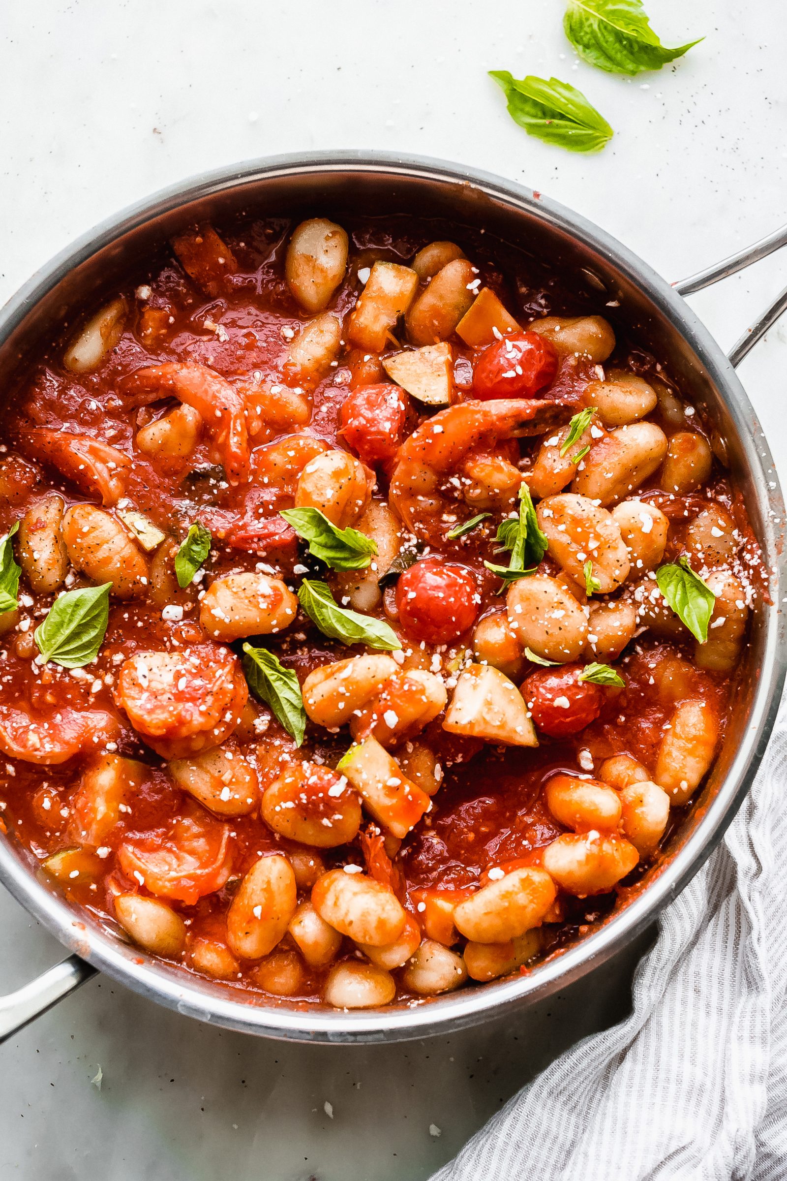 saute pan with prepared shrimp gnocchi in pomodoro sauce on white marble surface