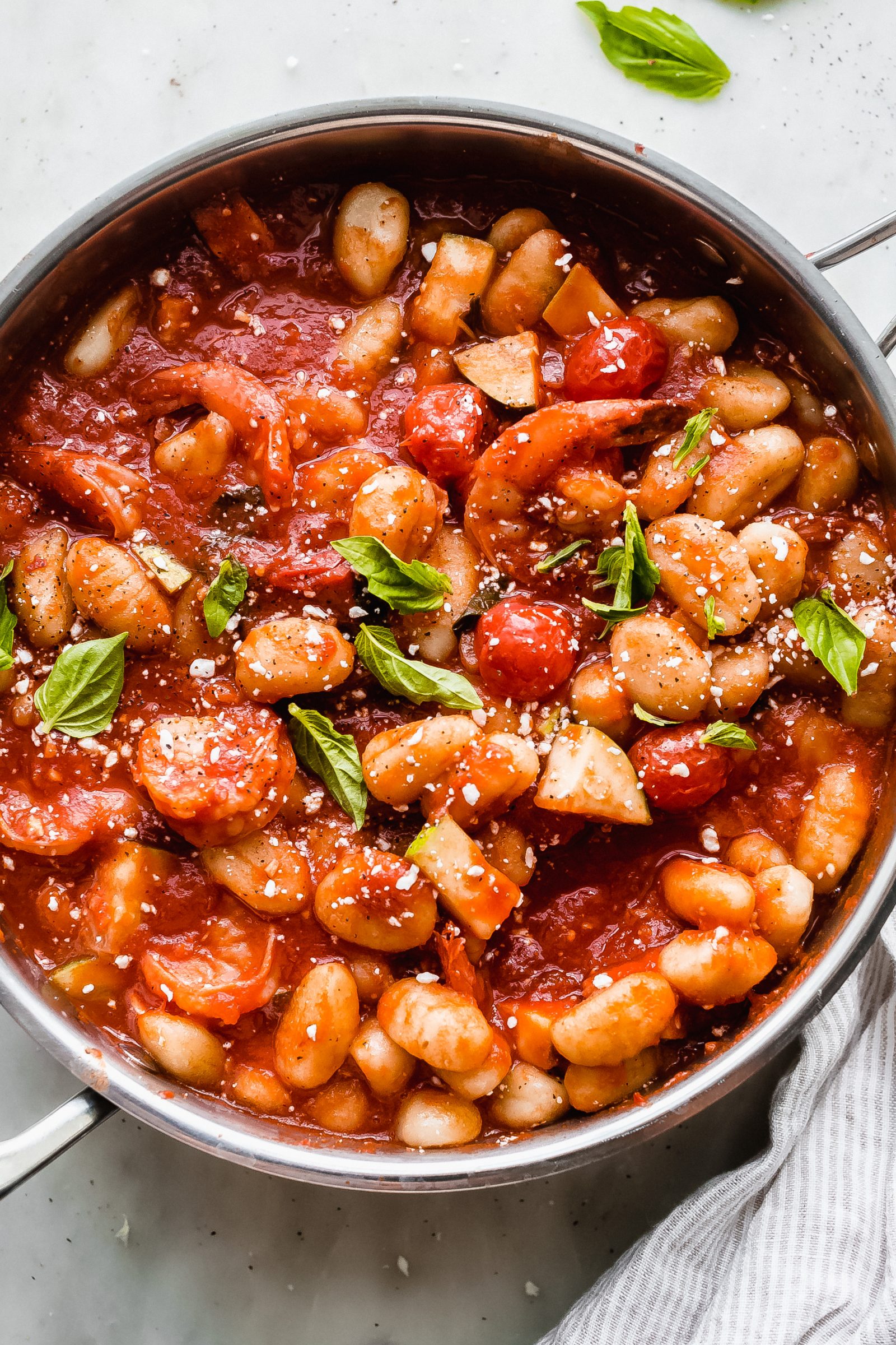 skillet with gnocchi in tomato sauce topped with basil