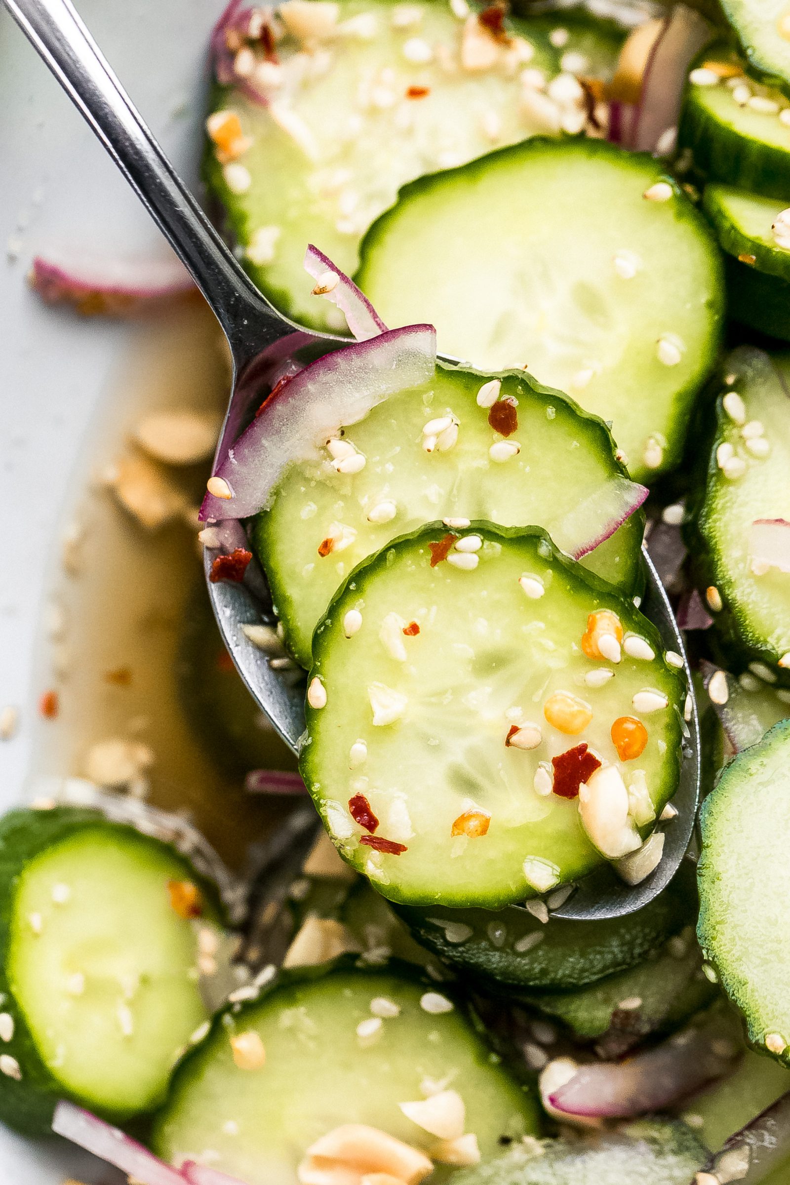 close up of Persian cucumber salad topped with red pepper flakes, sesame seeds, and red onions