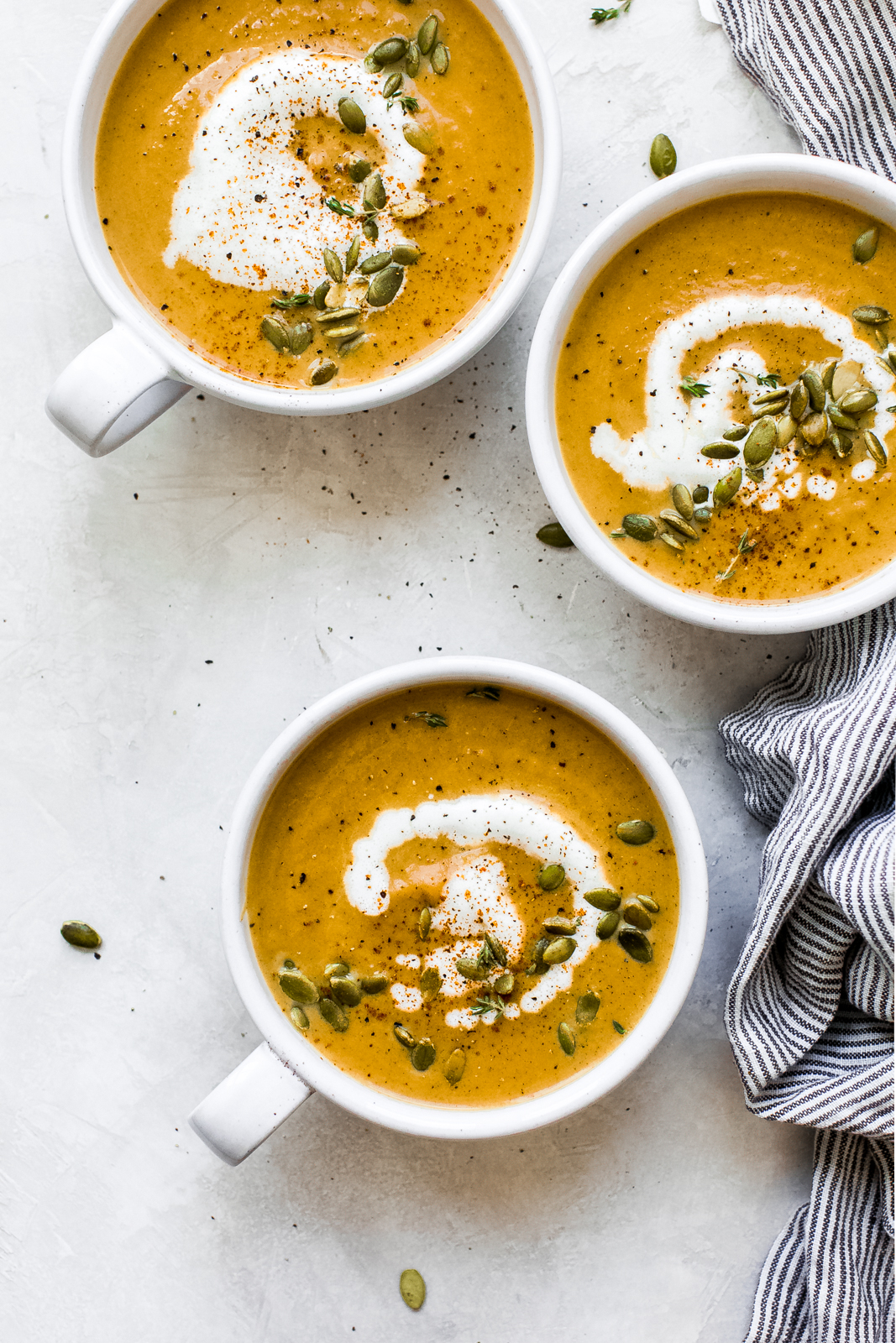 three bowls of pumpkin soup on grey and white surface