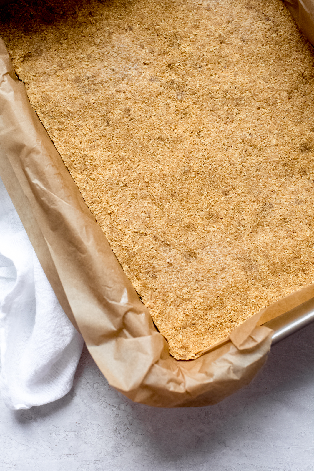 prepared graham cracker crust pressed into a baking dish with parchment 